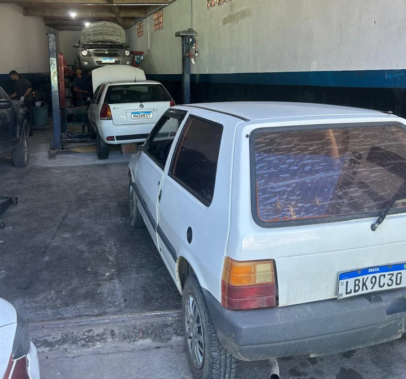 Interior da LUANs Oficina Mecânica: carros nos elevadores e equipe trabalhando
